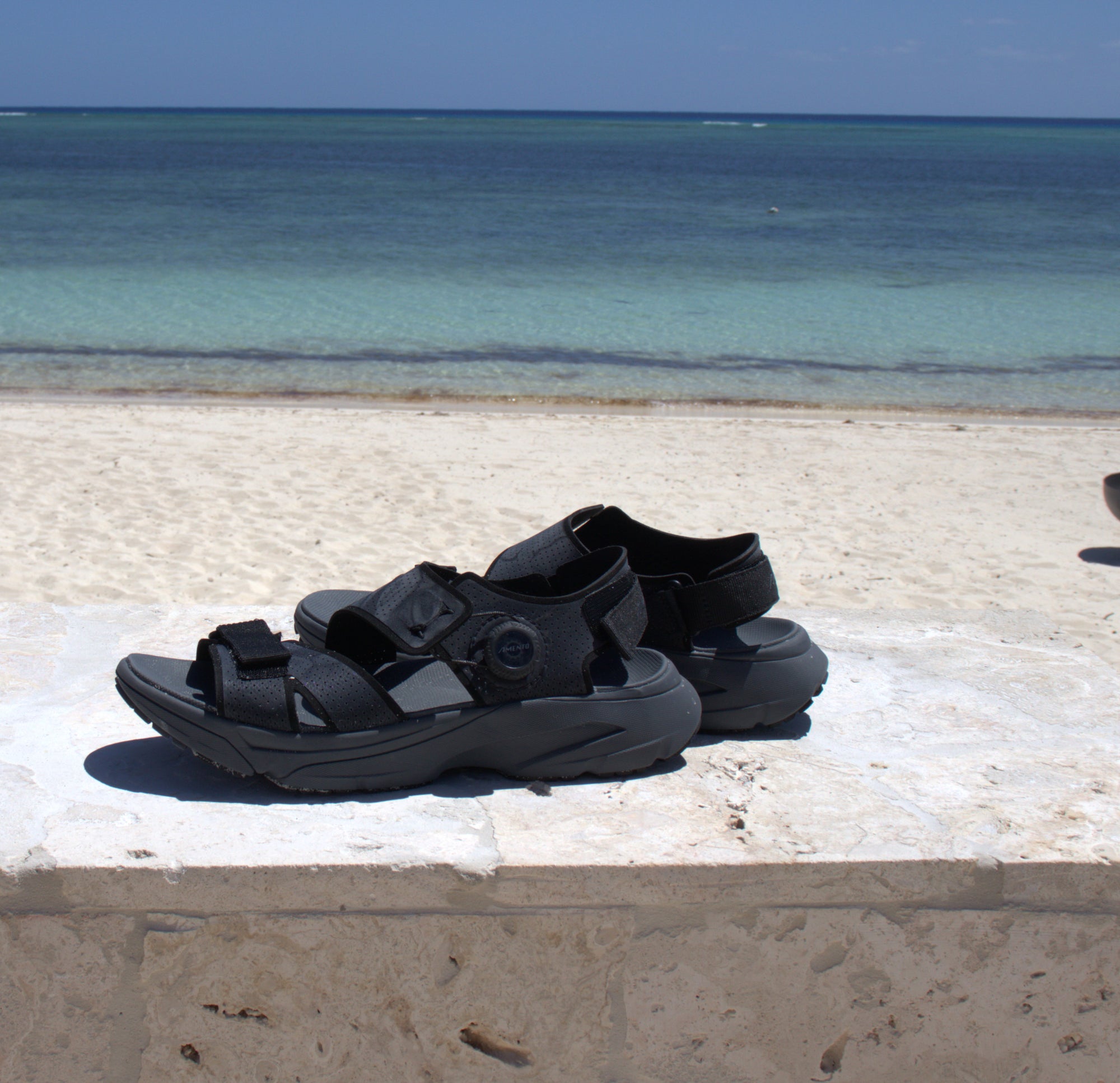 mens Amento Wingra in block on seawall with turquoise ocean in background