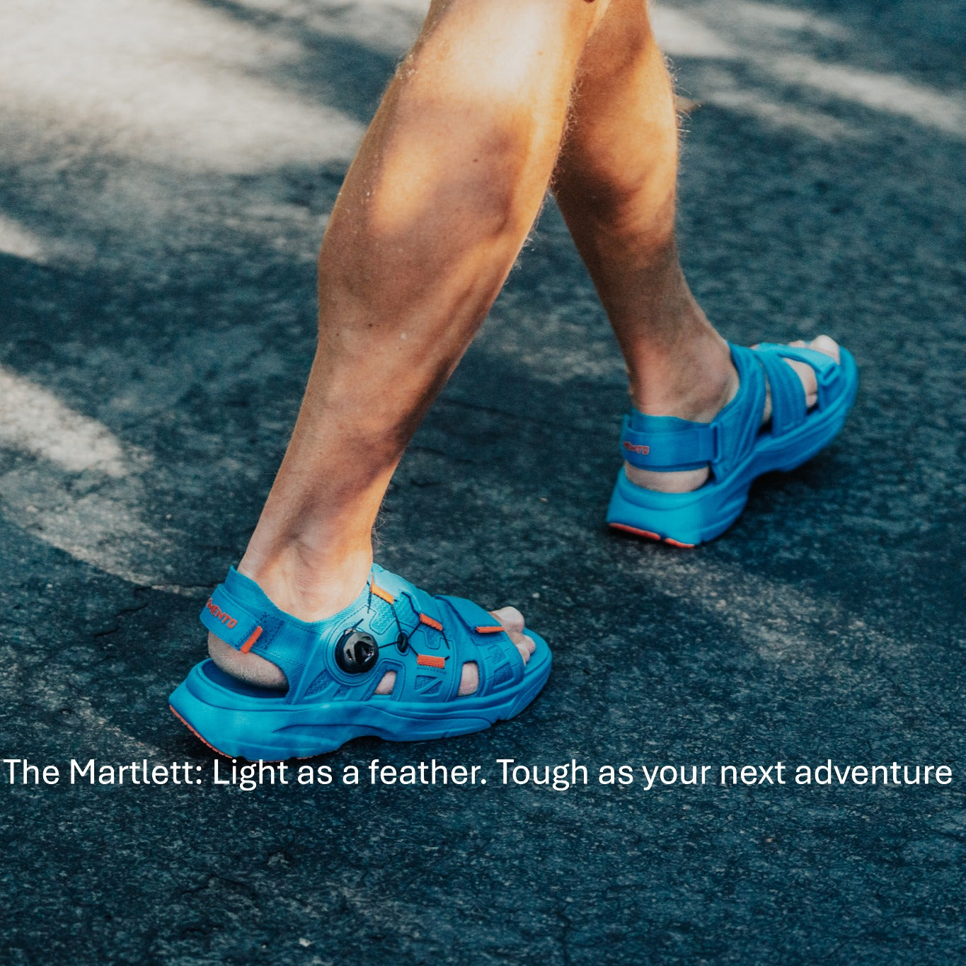 "Person walking on pavement wearing bright blue Amento Martlett sandals, designed for lightweight durability and adventure"